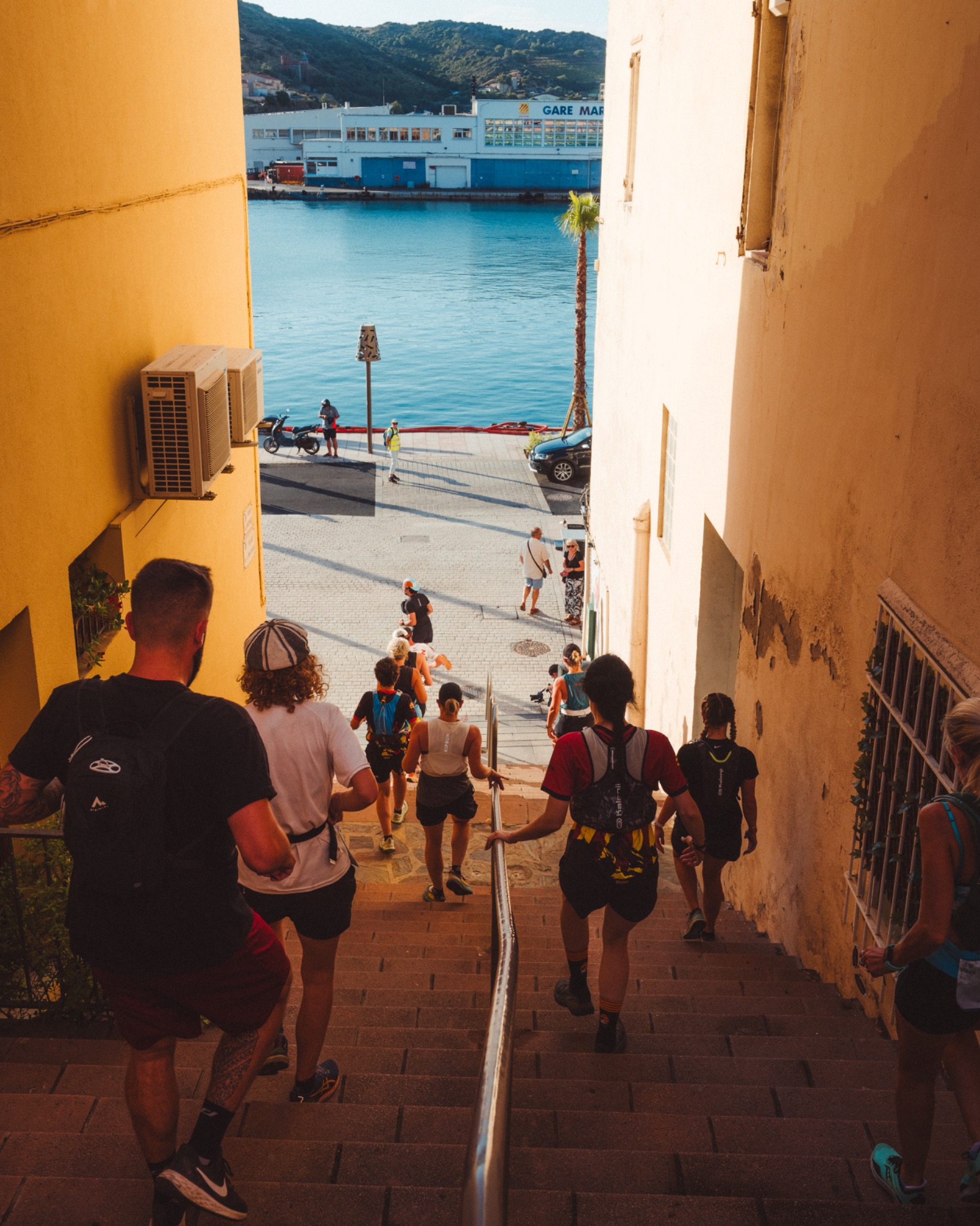 Coureurs descendant les escaliers avec vue sur le port de Port-Vendres